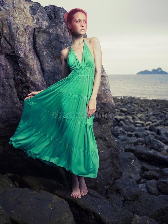 Beautiful lady in a green dress on a rocky shore. Beautiful lady in a green dress on a rocky shore