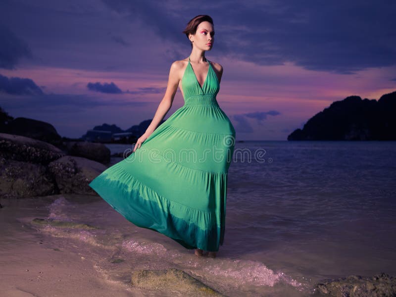Beautiful lady in a green dress on a rocky shore. Beautiful lady in a green dress on a rocky shore