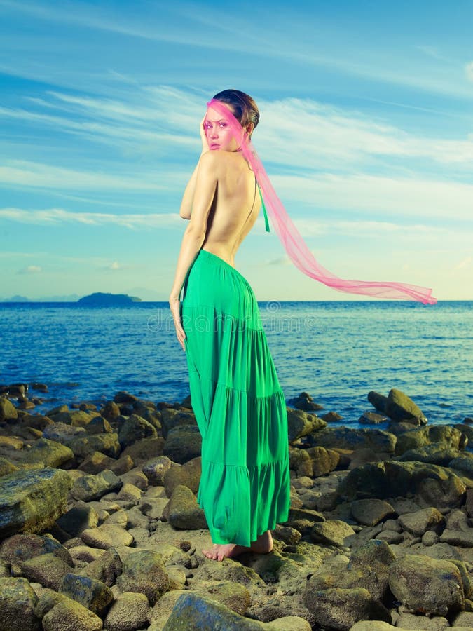 Beautiful lady in a green dress on a rocky shore. Beautiful lady in a green dress on a rocky shore