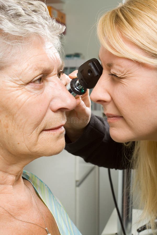 An older lady taking an eyesight test examination at an optician clinic. An older lady taking an eyesight test examination at an optician clinic