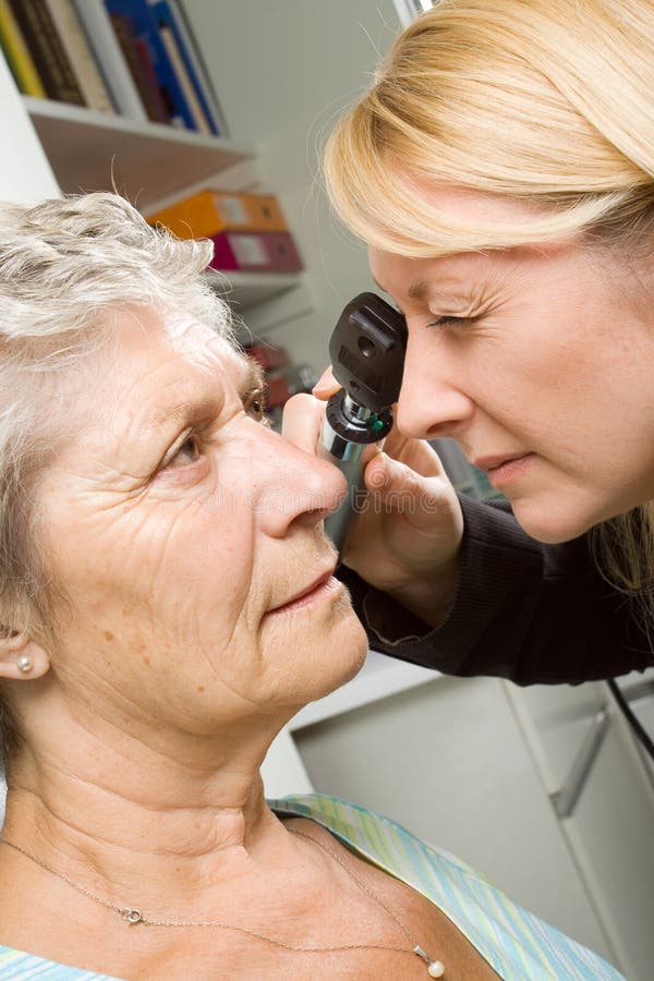 An older lady taking an eyesight test examination at an optician clinic. An older lady taking an eyesight test examination at an optician clinic