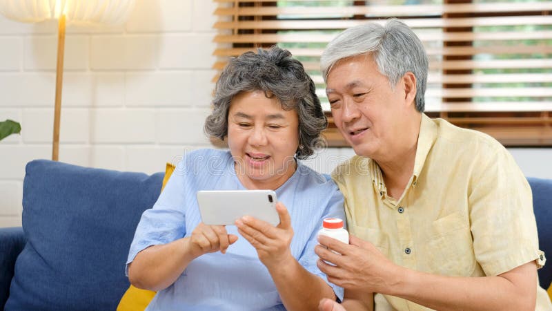 Senior asian couple holding bottle of pill make video conference call to doctor, pharmacy consulting about pill for medical health