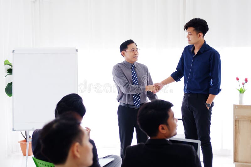 Senior Asian Lecturer is shaking hand with young businessman for congratulate on the success of his work and business. Stock