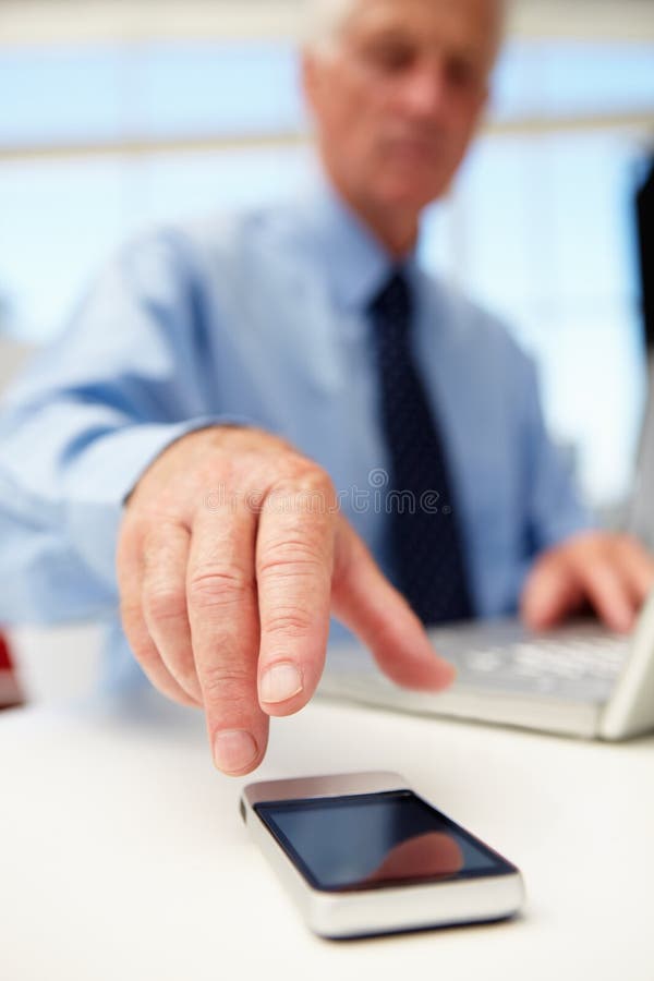 Senior businessman with laptop and phone stock photography