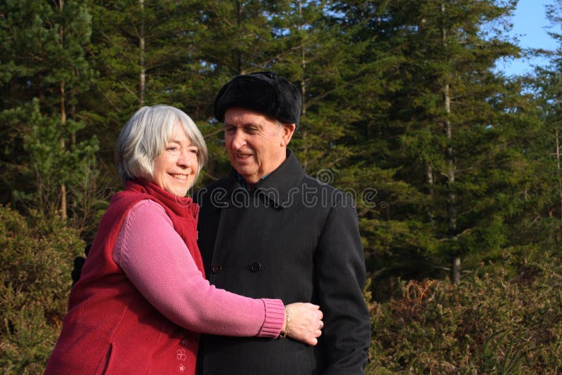 Senior couple enjoy woodland walk.