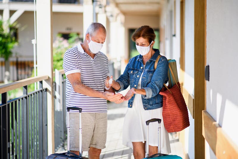 Senior Couple with Face Masks and Luggage Outside Apartment on Holiday ...