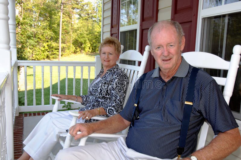 A happy senior couple sitting on the front porch of a home in rocking chairs. A happy senior couple sitting on the front porch of a home in rocking chairs