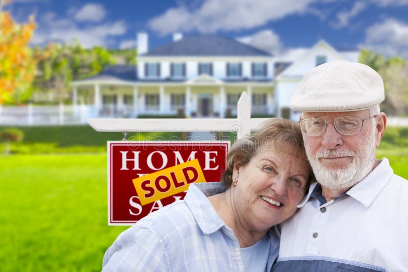 Happy Affectionate Senior Couple Hugging in Front of Sold Real Estate Sign and House. Happy Affectionate Senior Couple Hugging in Front of Sold Real Estate Sign and House.