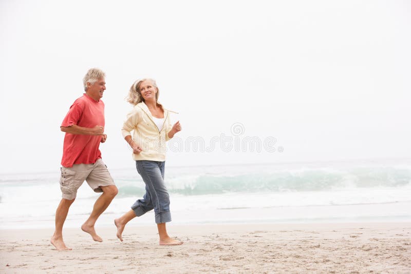 Senior Couple On Holiday Running Along Beach royalty free stock photography Senior Couple On Holiday Running Along Beach royalty free stock photography