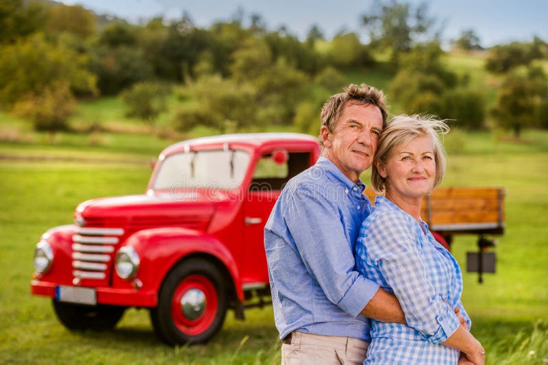 Senior Couple Hugging, Vintage Styled Red Car, Sunny Nature Stock Photo ...