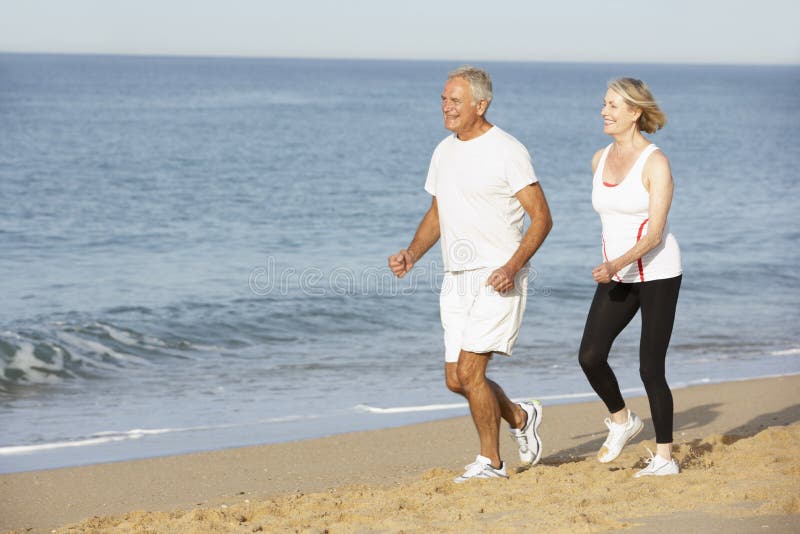 Senior Couple Jogging Along Beach