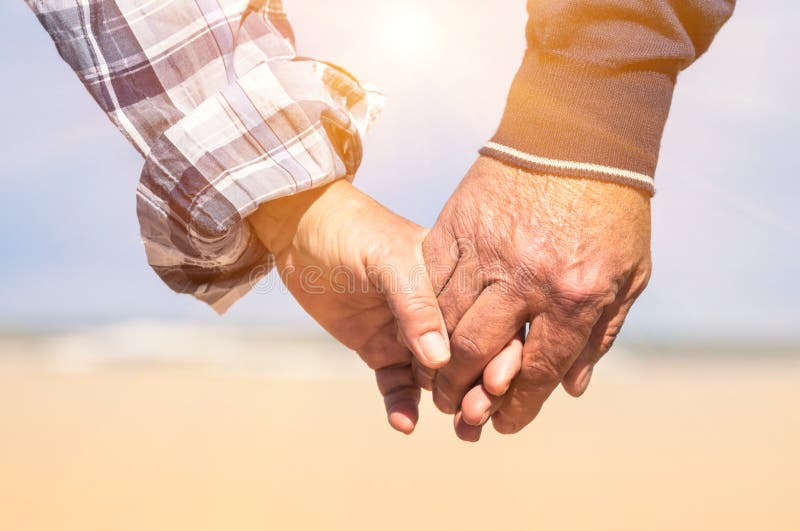 Senior pár v lásce procházky na pláži se drží za ruce v romantickém slunečný den Pojetí lásky a rodinné unie.