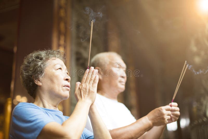 Senior couple praying buddha with incense stick