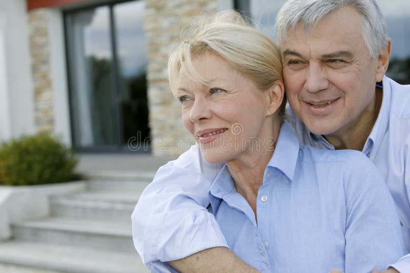 Senior couple standing on front of their new home