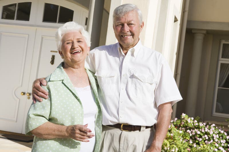 Senior couple standing outside front door of home. Senior couple standing outside front door of home