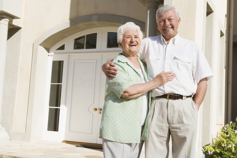 Senior couple standing outside front door of house. Senior couple standing outside front door of house