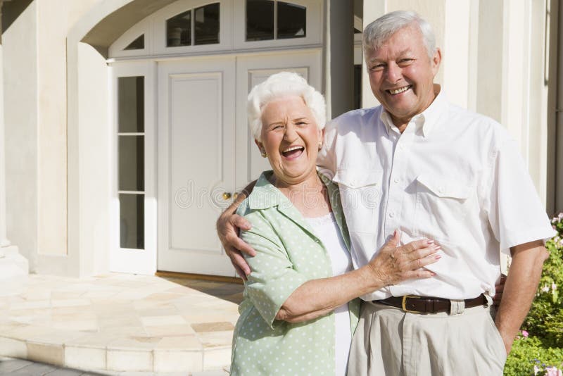 Senior couple embracing outside house. Senior couple embracing outside house