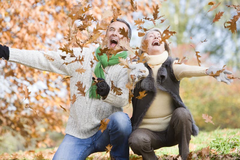 Senior couple throwing autumn leaves in the air. Senior couple throwing autumn leaves in the air