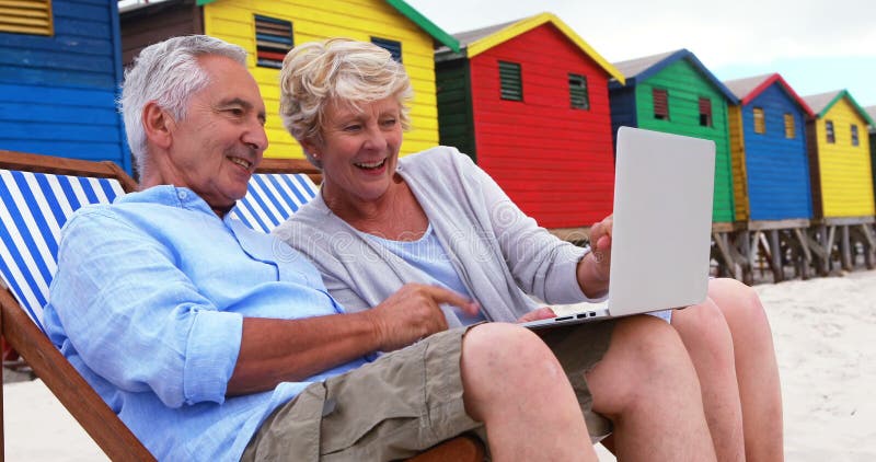 Senior couple using laptop at the beach