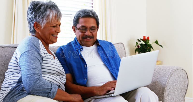 Senior couple using laptop in living room 4k