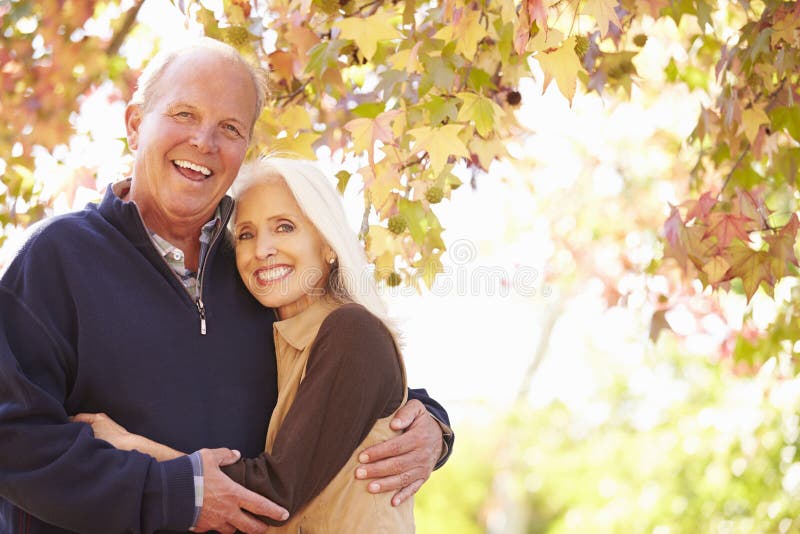 Senior Couple Walking Through Autumn Woodland