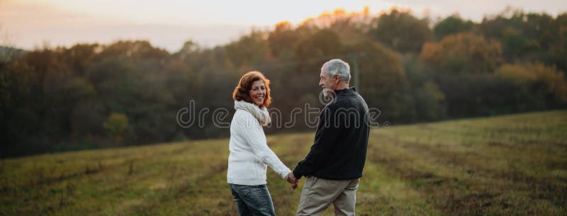 Loving senior couple walking hand by hand in autumn sunset light. Joyful loving elderly couple stock images, royalty-free photos and pictures
