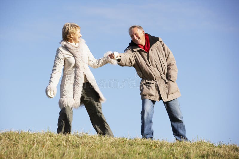 Senior Couple Walking In Park Wearing Winter Coats