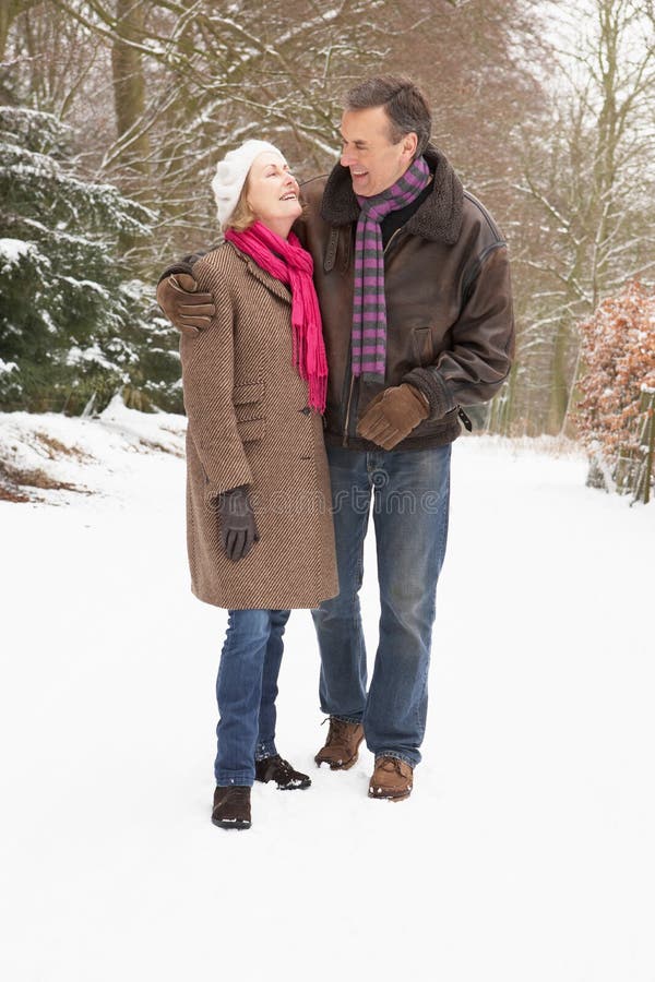 Senior Couple Walking Through Snowy Woodland