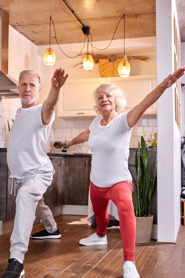 senior couple in warrior yoga pose, doing Virabhadrasana stock photos