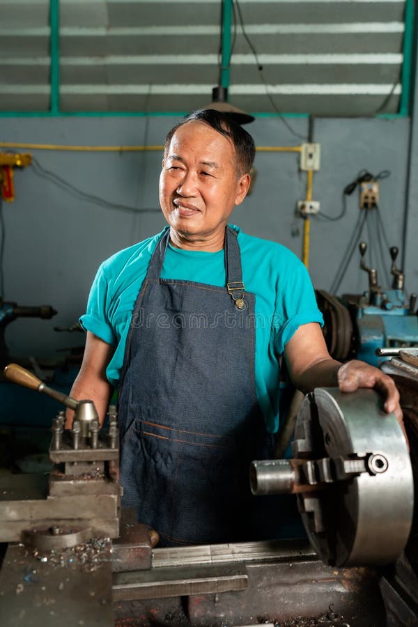 A senior craftsman who is skilled in craftsmanship, is controlling, skillfully operating a lathe, is in a small factory that is royalty free stock image