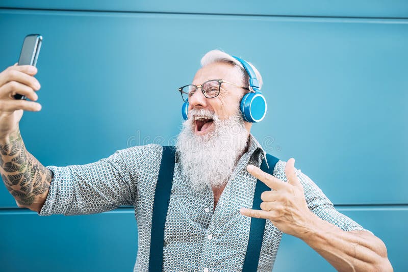 Senior crazy man taking self video while listening music with headphones - Hipster guy having fun using mobile smartphone stock images