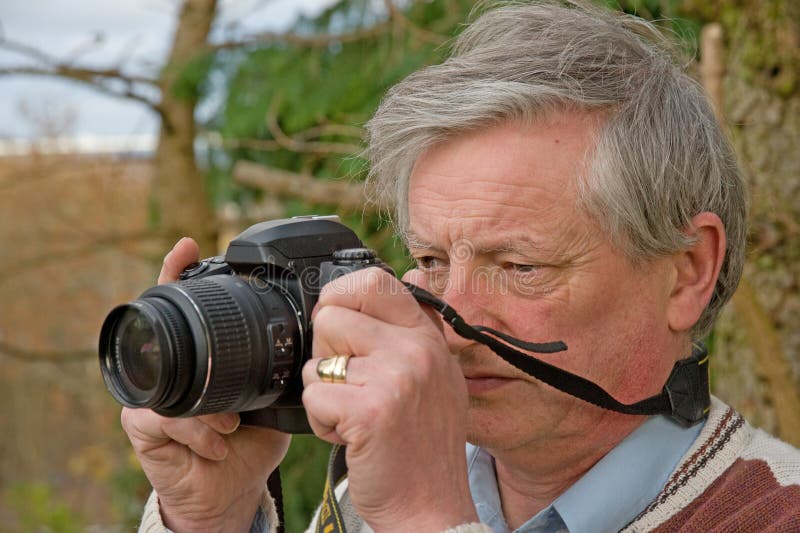 An image of a Senior in the garden photographing birds and wildlife with a ( DSLR ) digital camera. . An image of a Senior in the garden photographing birds and wildlife with a ( DSLR ) digital camera. .