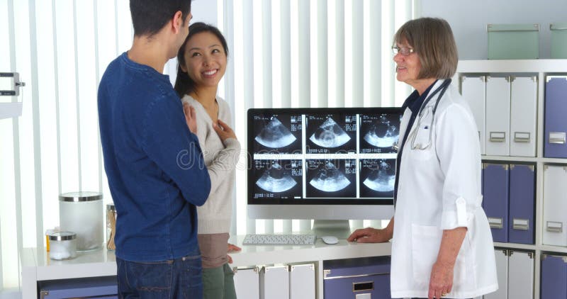 Senior doctor tells interracial couple about pregnancy stock photo Senior doctor tells interracial couple about pregnancy stock photo