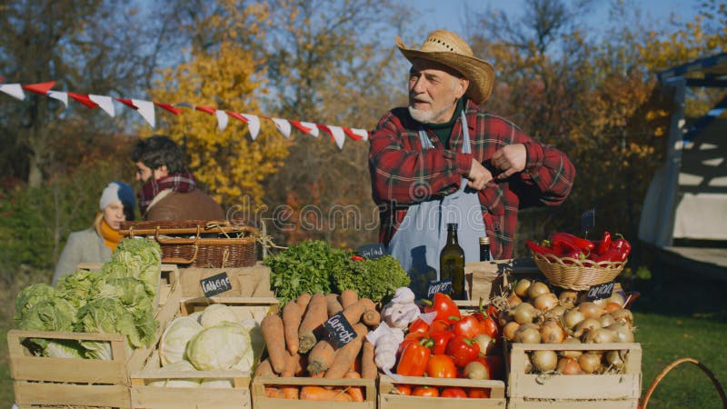 Zemědělec prodavač stojany na stání a zelenina, počítá hotovost peníze.