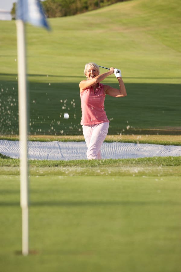 Senior Female Golfer Playing Bunker Shot
