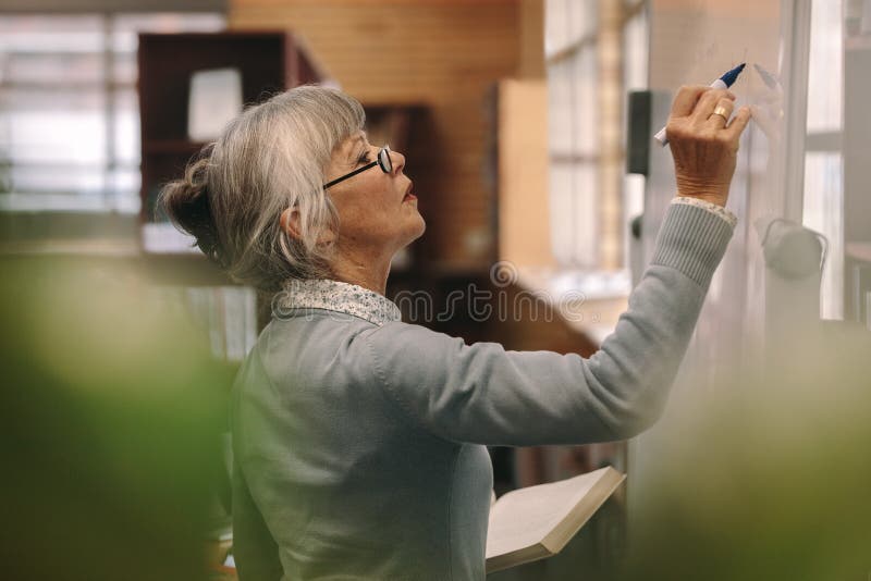 Senior female lecturer writing on board stock image Senior female lecturer writing on board stock image