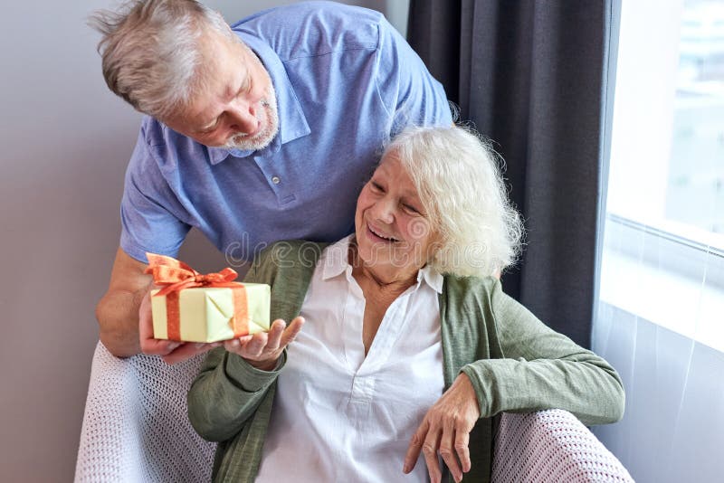 senior female person with satisfied face getting present box by her husband royalty free stock photos