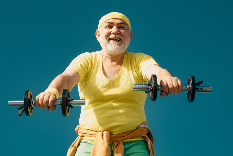 Senior fitness man training with dumbbells isolated on blue background. Lifting dumbbells. Portrait of senior man