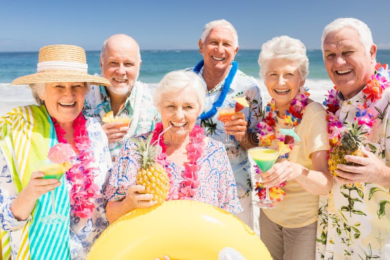 senior-friends-drinking-cocktails-beach-