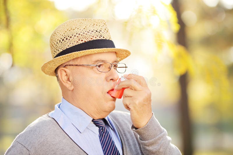 Senior gentleman taking asthma treatment in a park