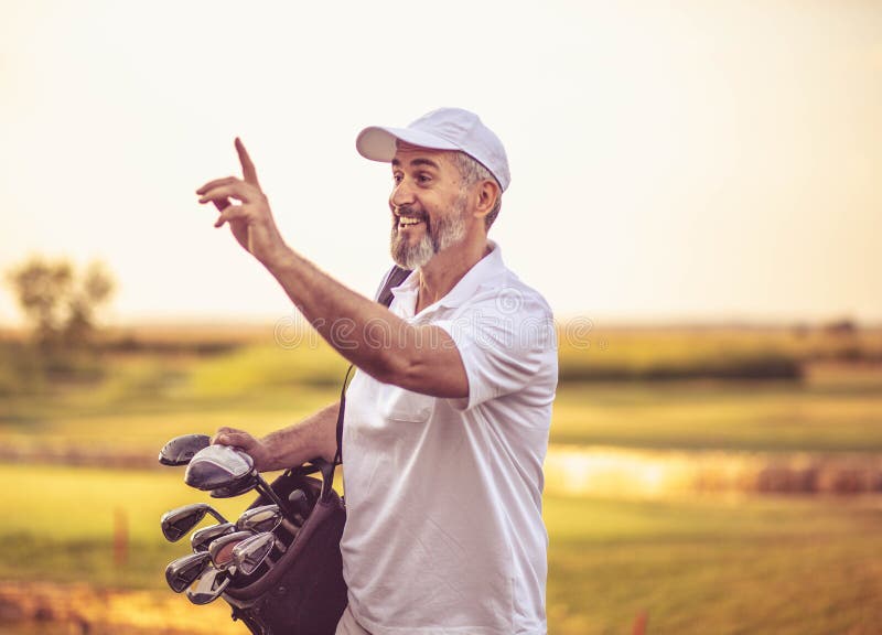 Senior golfer walking on golf court with bag.