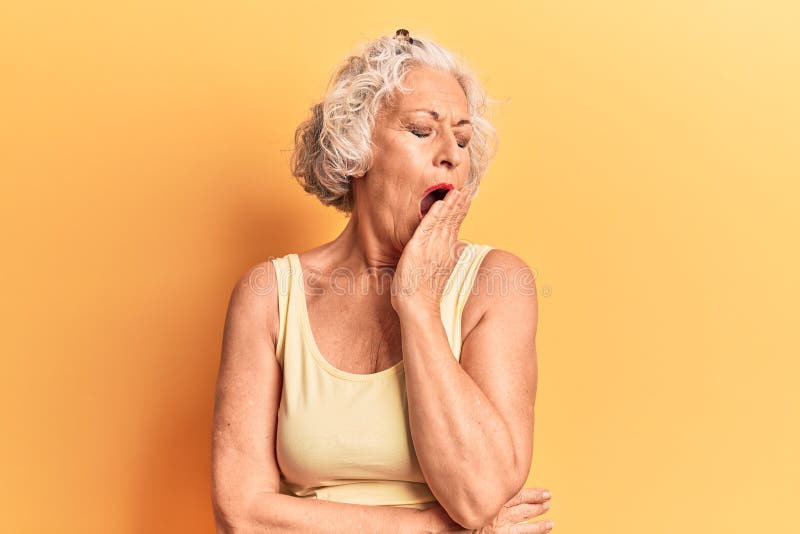 Senior grey-haired woman wearing casual clothes bored yawning tired covering mouth with hand