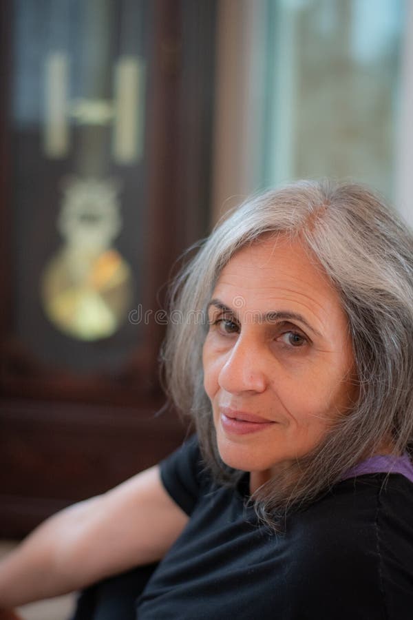 Senior Indian woman with grey hair and glowing skin, meditating in the morning.