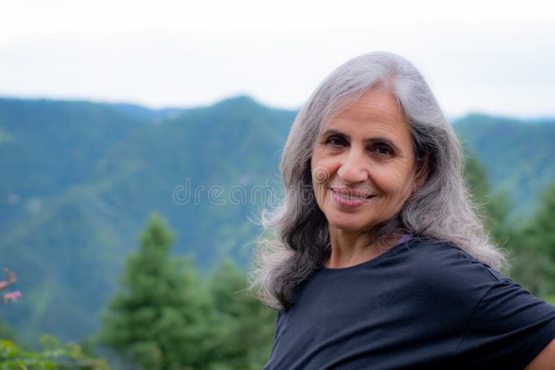 Senior Indian woman with grey hair and glowing skin, meditating in the morning.
