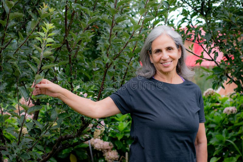 Senior Indian woman with grey hair and glowing skin, meditating in the morning.