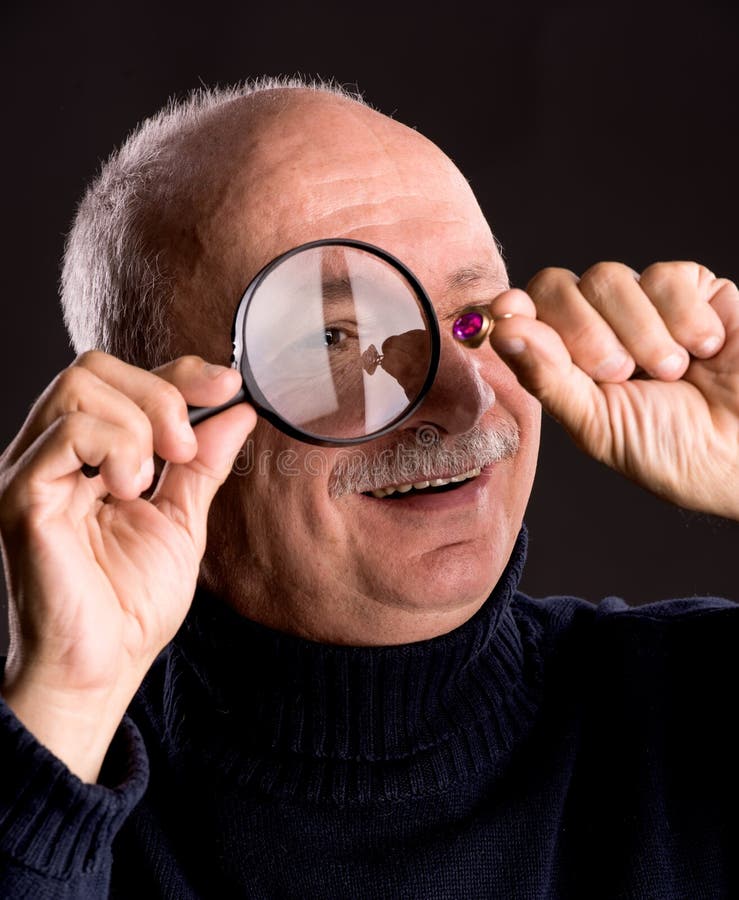 Senior jeweler examining a ring with magnifying glass stock photo