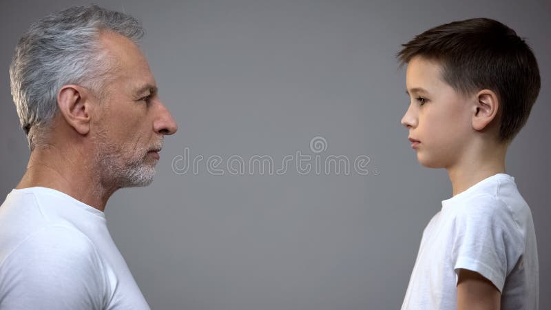 Senior male and teen boy maintaining eye contact, generation gap, aging royalty free stock photography Senior male and teen boy maintaining eye contact, generation gap, aging royalty free stock photography