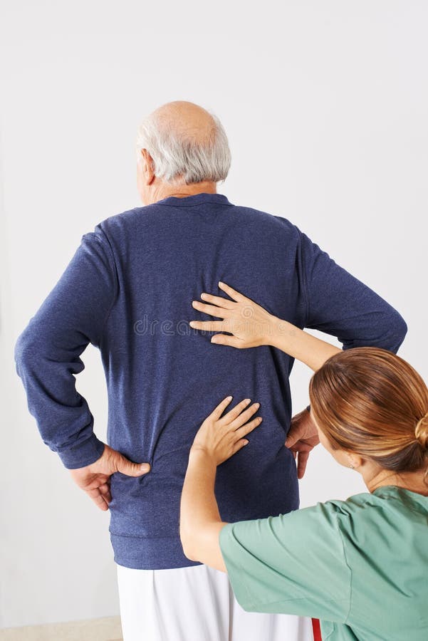 Physiotherapist laying hands on senior men with back pain in physical therapy. Physiotherapist laying hands on senior men with back pain in physical therapy