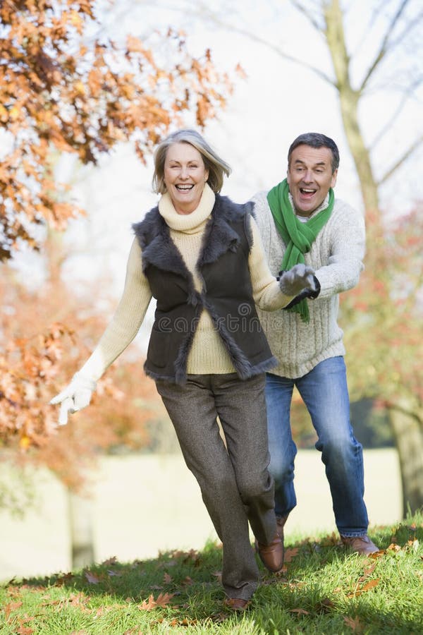 Senior man chasing woman through countryside stock photo Senior man chasing woman through countryside stock photo