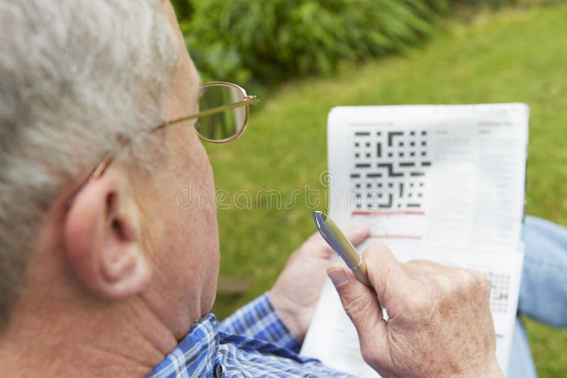 Senior Man Doing Crossword Puzzle In Garden